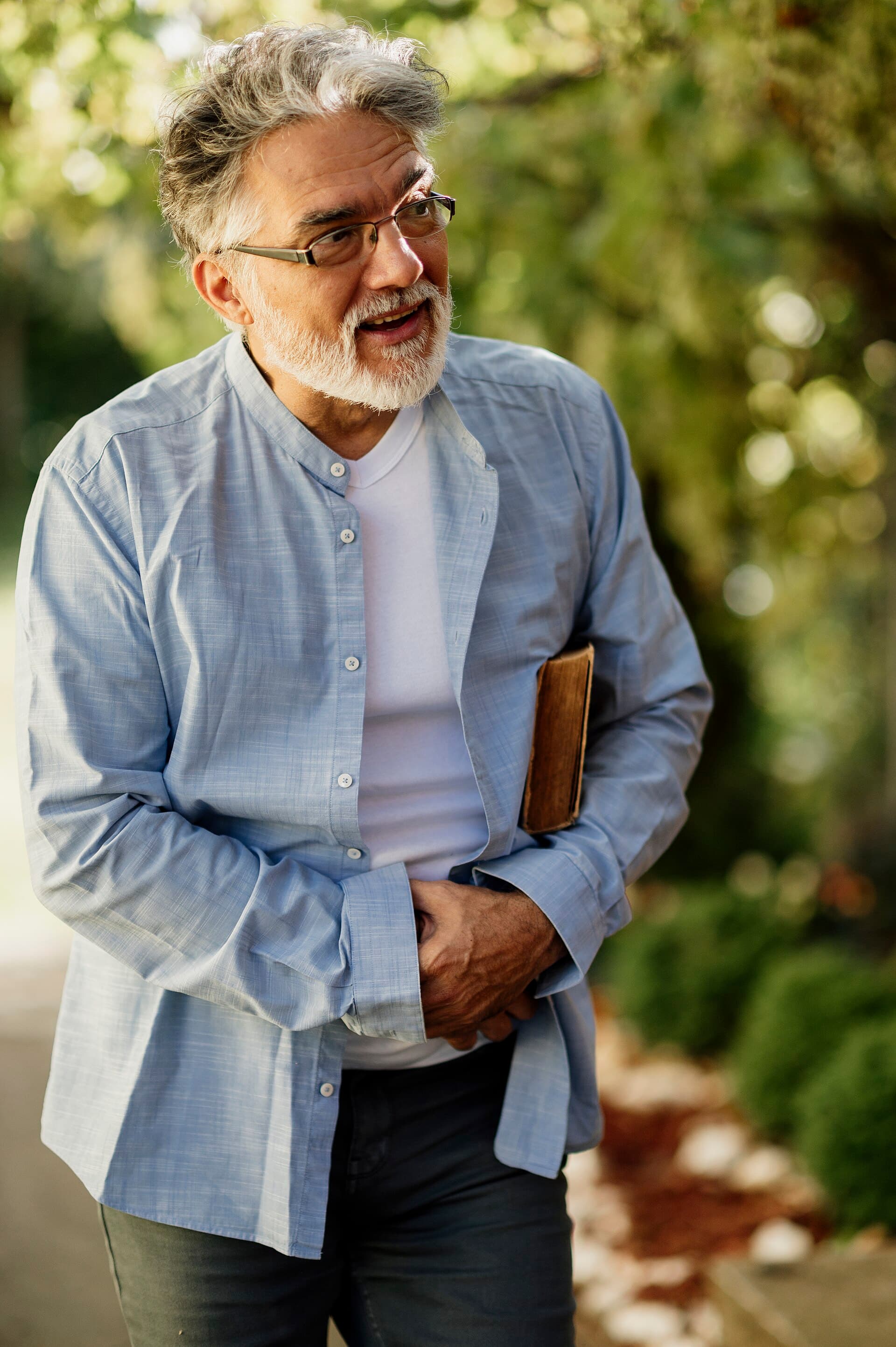 An older man walking in a park on a sunny day
